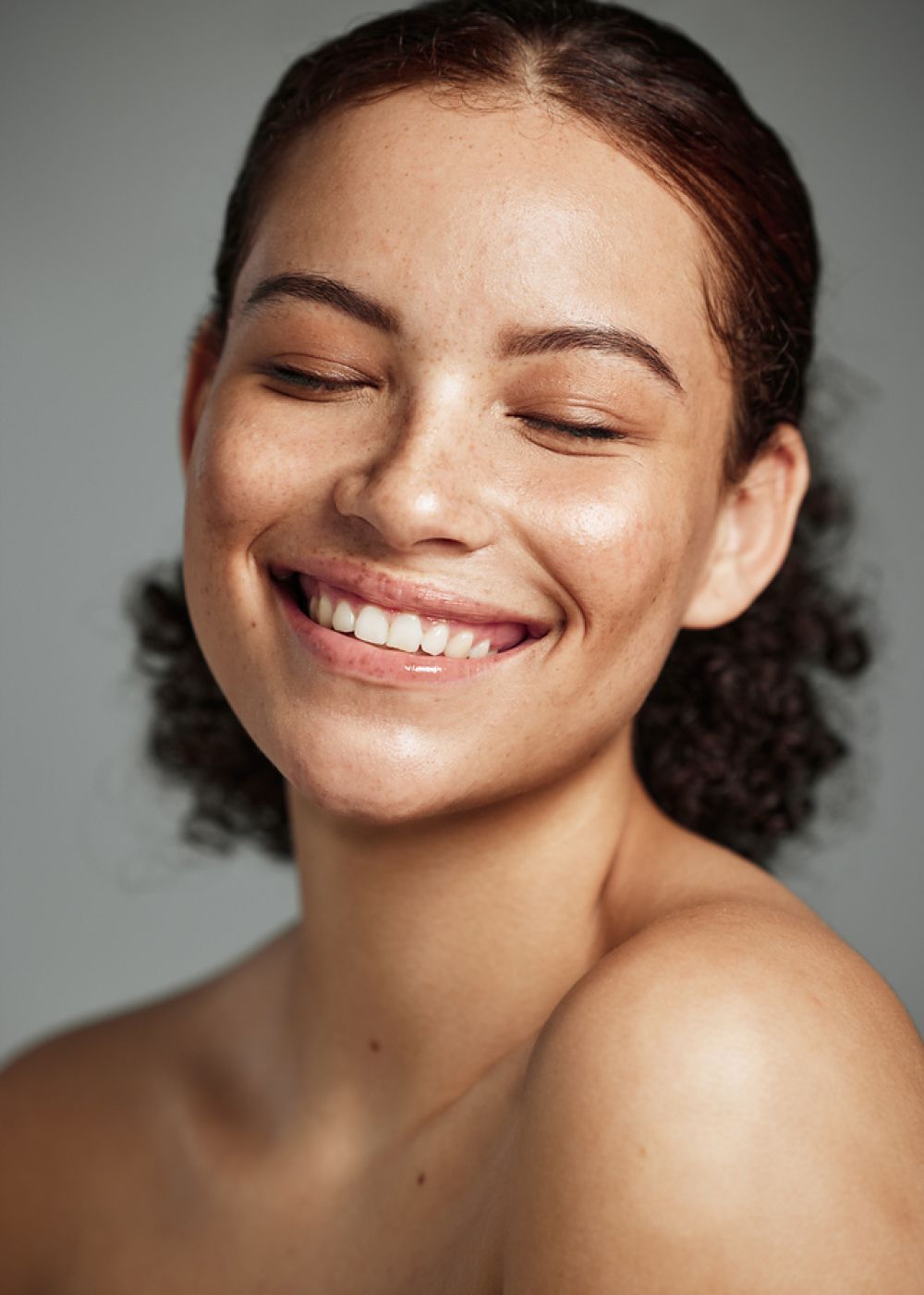 Smiling woman with freckled skin and curly hair.